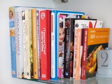 A shelf with a row of cookbooks and cooking guides at The Beach Hut in Polzeath