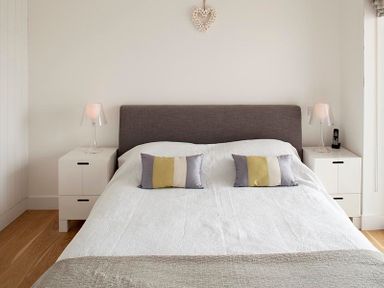 A bedroom with a double bed two pillows two bedside tables with lamps and a phone at The Beach Hut in Polzeath