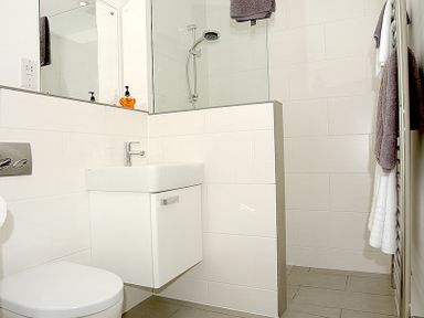 A bathroom with a toilet sink mirror walk in shower and towels at The Beach Hut in Polzeath