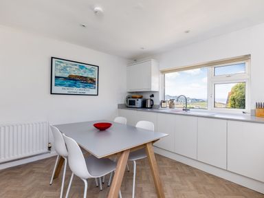A kitchen with a dining table and chairs next to a window with a view at Bella Vista in Polzeath