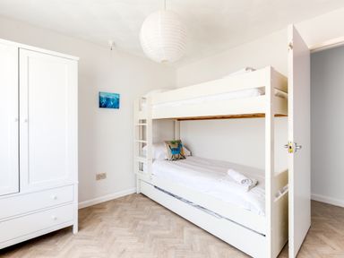 A bedroom with a bunk bed a white wardrobe and a hanging light at Bella Vista in Polzeath