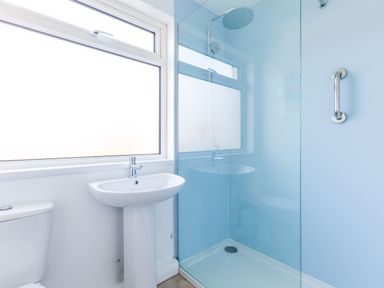 A bathroom with a toilet a pedestal sink and a glass-enclosed shower at Bella Vista in Polzeath