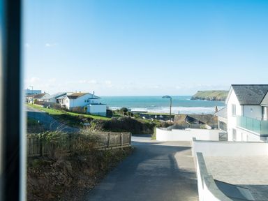 A coastal street view with houses and the sea in the background at Pinewood Flat 5 in Polzeath