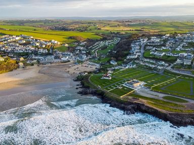 A coastal village with houses roads and green fields beside a beach and ocean at Pinewood Flat 5 in Polzeath