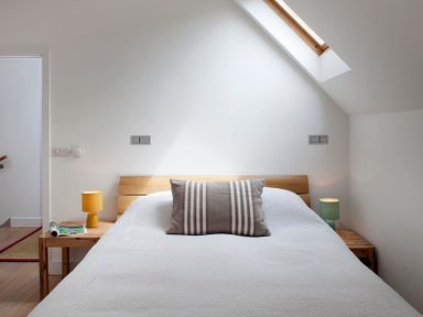 A bedroom with a bed a striped pillow and two bedside tables with lamps at Kellan in Polzeath