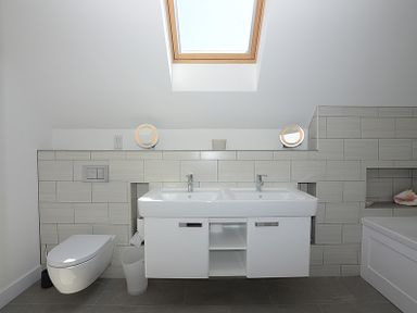 A bathroom with double sinks a toilet a bathtub and a skylight at Kellan in Polzeath