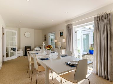 A dining room with a white table and chairs set with plates and glassware with glass doors leading outside at The Moorings in Rock