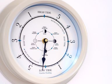A tide clock showing high tide low tide and moon phases on a white wall at The Moorings in Rock