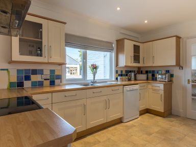 A kitchen with cream cabinets blue and yellow tiled backsplash a window with a blind and appliances at The Moorings in Rock