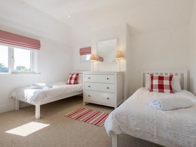 A bedroom with two single beds with red and white pillows a dresser with two lamps and a mirror at The Moorings in Rock