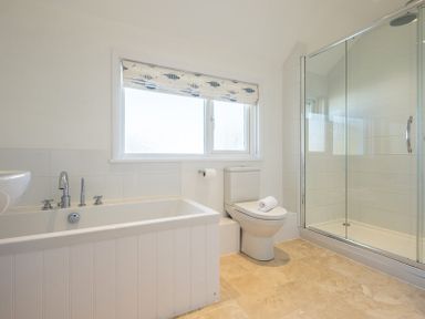 A bathroom with a bathtub toilet and glass shower enclosure at The Moorings in Rock