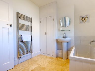 A bathroom with a towel radiator sink with mirror storage cabinet and bathtub at The Moorings in Rock