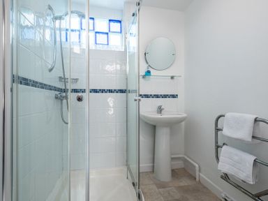 A bathroom with a shower enclosure sink mirror and towel rack at The Moorings in Rock