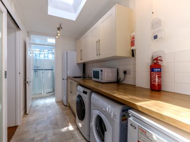 A utility room with a washing machine dryer microwave fridge freezer shower at The Moorings in Rock