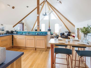 A kitchen and dining area with wooden cabinets blue countertops a dining table set with plates and glasses and a seating area with chairs and a wood stove at Sandy Hills 8 in Rock