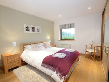 A bedroom with a double bed with white bedding and a purple throw at Sandy Hills 8 in Rock