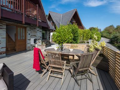 An outdoor patio with a round wooden table and chairs near a house with a stone exterior at Sandy Hills 8 in Rock