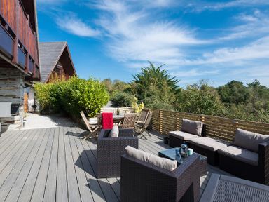 An outdoor deck with patio furniture wooden chairs and a table surrounded by greenery at Sandy Hills 8 in Rock