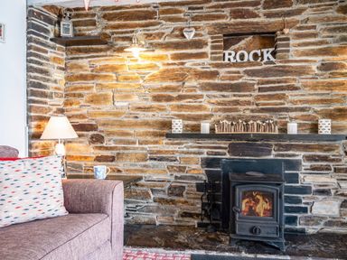A stone wall with a burning wood stove mantel and a purple sofa with a pillow at St Michaels Rock