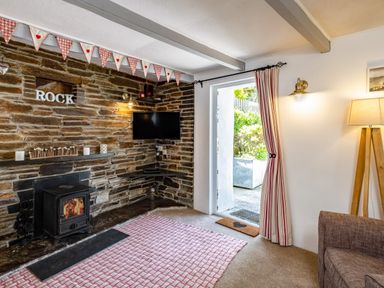 A living room with a stone fireplace wood stove television open door and striped curtains at St Michaels in Rock