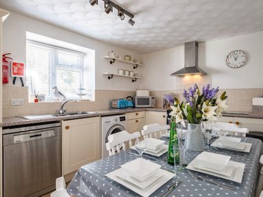 A kitchen with a dining table set for four with flowers on the table at St Michaels in Rock