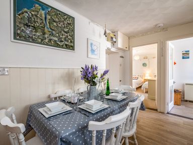 A dining room with a table set for six and flowers in a vase at St Michaels in Rock