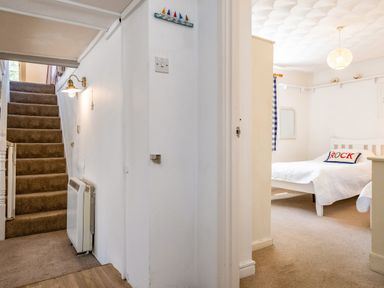 A hallway with carpeted stairs and a bedroom with a double bed and a pillow with rock on it at St Michaels in Rock