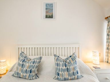 A bedroom with a white bed frame with blue and beige patterned pillows and lamps on side tables at St Michaels Rock