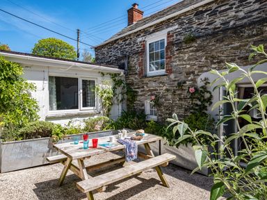 A stone house exterior with a wooden picnic table and benches in a garden at St Michaels Rock