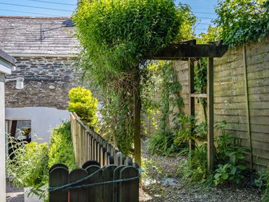 A garden path with wooden fence and pergola covered in greenery at St Michaels in Rock
