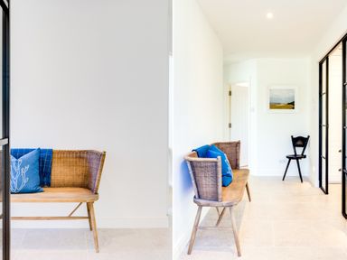 A hallway with a wicker bench with blue cushions and a black wooden chair at Greystones in Daymer Bay