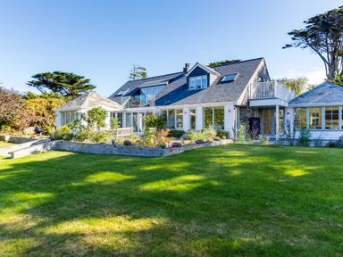 A large house with a garden and a stone wall under a clear sky at Greystones in Daymer Bay