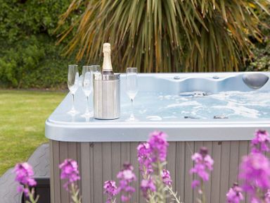 An outdoor hot tub with champagne bottle in ice bucket and four champagne flutes at Cherrytrees in Rock
