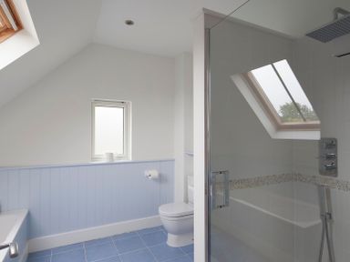 A bathroom with a toilet bathtub and glass shower enclosure with a skylight window at Cherrytrees in Rock