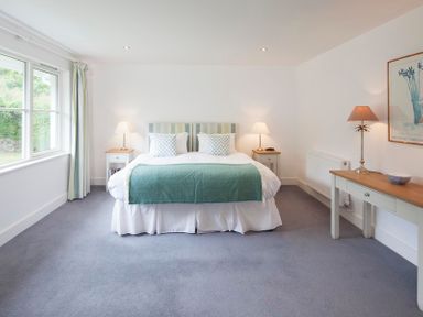 A bedroom with a double bed two bedside tables lamps a console table and a window at Cherrytrees Rock