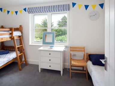 A bedroom with a wooden bunk bed a white dresser a wooden chair and a single bed at Cherrytrees in Rock