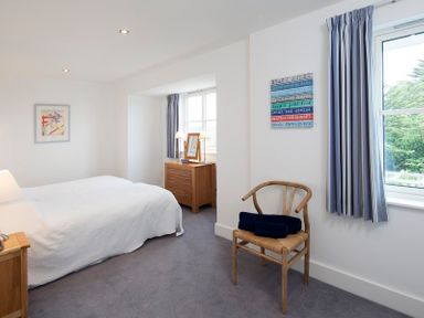 A bedroom with a bed a wooden chair and a chest of drawers with two lamps at Cherrytrees in Rock