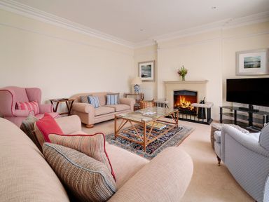 A living room with sofas armchairs a glass coffee table fireplace and a television at The Haven in Daymer Bay