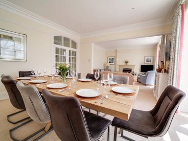 A dining table set with plates and glasses in a room with chairs and an adjoining living area at The Haven in Daymer Bay
