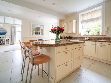A kitchen with a granite countertop island with flowers on top and chairs at The Haven in Daymer Bay