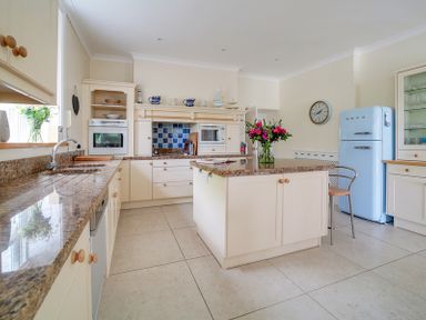 A kitchen with an island countertop a blue refrigerator and white cabinets at The Haven in Daymer Bay