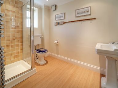 A bathroom with a shower enclosure toilet with a decorative seat and a pedestal sink at The Haven in Daymer Bay