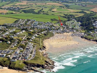 An aerial view of a coastal town with a beach fields houses and roads at Pendaveli in Polzeath