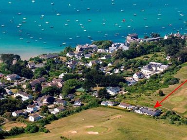An aerial view of a coastal village with houses near the shoreline and boats in the water at Penny Liggan in Rock