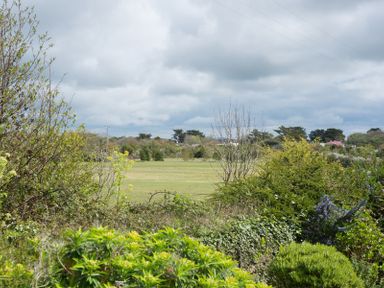 A landscape with green bushes, trees, a grassy field and cloudy sky at Penny Liggan in Rock