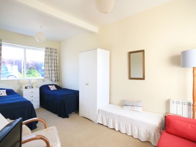 A bedroom with two single beds blue bedspreads white wardrobe and bench at The Holiday House 2 Atlantic Mews in Polzeath