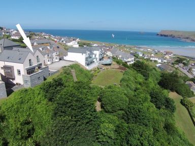 A coastal village with houses near a beach and green vegetation at Stepper Point in Polzeath