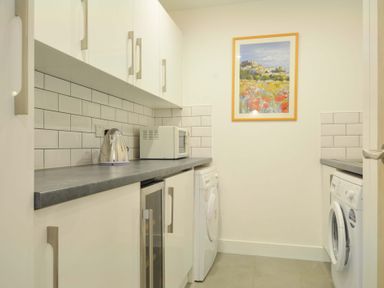A laundry room with appliances and wall art at Stepper Point in Polzeath