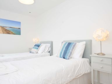 A bedroom with two single beds and a nightstand at Stepper Point in Polzeath