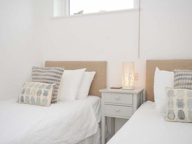 A bedroom with two beds and a lamp on a bedside table at Stepper Point in Polzeath
